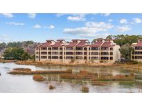 Scenic condo building overlooking lake, offering serene waterfront living with beautiful landscaping and a tranquil atmosphere at 501 Maison Dr. # F12, Myrtle Beach, SC 29572
