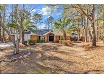Charming brick home featuring mature trees, palm trees, and manicured landscaping at 1165 Carnoustie Ct., Myrtle Beach, SC 29575