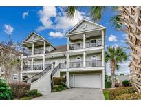 Three-story home with a grand staircase, attached garage, and lush landscaping at 4417 N Plantation Harbour Dr. # B, Little River, SC 29566