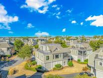 Expansive aerial view of a neighborhood showcasing uniform, stylish homes with rooftop decks under a bright blue, cloudy sky at 1609 Harbor Dr., North Myrtle Beach, SC 29582