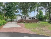 Park model home with deck, brick driveway, and landscaped lawn at 6001 - 8047 S Kings Hwy., Myrtle Beach, SC 29575