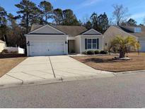 Tan house with two-car garage and landscaping at 895 Callant Dr., Little River, SC 29566