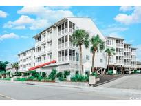 Oceanfront building, featuring a light-colored exterior and palm trees at 9571 Shore Dr. # 119, Myrtle Beach, SC 29572