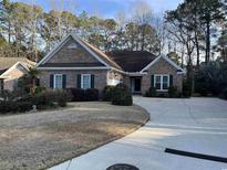 Charming brick home featuring manicured lawn, mature trees, and a long driveway at 35 Dornoch Dr., Pawleys Island, SC 29585