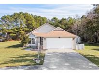 Tan house with a white garage door and landscaping at 518 Cordgrass Ln., Little River, SC 29566