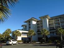 Building exterior showcasing a condo building with palm trees and ample parking at 601 Retreat Beach Circle # 128, Pawleys Island, SC 29585