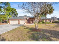 Brick home with three-car garage and manicured lawn at 8223 Forest Lake Dr., Conway, SC 29526