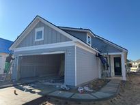 View of the house being painted with an open garage, showcasing its modern design at 1245 Lady Bird Way, North Myrtle Beach, SC 29582