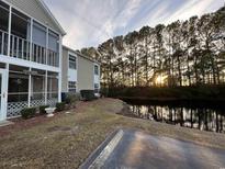 Exterior view of condo building showcasing a screened porch and a tranquil waterfront setting at 1925 Bent Grass Dr. # B, Surfside Beach, SC 29575