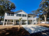 Charming stilt house with white siding, dark shutters and spacious carport at 2509 Ye Olde Kings Hwy., North Myrtle Beach, SC 29582