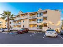 The building features a bright yellow exterior with multiple balconies and ample parking spaces at 1100 Possum Trot Rd. # H234, North Myrtle Beach, SC 29582