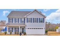 Charming two-story home featuring blue shutters, a well-manicured lawn, and an attached two-car garage at 1213 Pineridge St., Conway, SC 29527