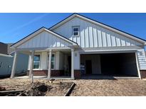 Charming single-story home featuring vertical siding, a covered porch, and an attached garage, with landscaping in progress at 1305 Crested Iris Way, North Myrtle Beach, SC 29582