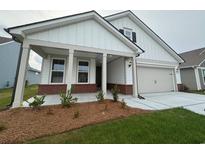 Charming home with white siding, a brick-accented porch, and a well-manicured lawn, inviting curb appeal at 1305 Crested Iris Way, North Myrtle Beach, SC 29582