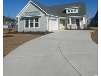 Gray house with a yellow door, two car garage, and a long driveway at 1001 Gold Dew Way, Myrtle Beach, SC 29579