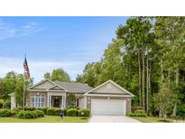 Tan brick ranch home with attached garage, landscaping, and American flag at 905 Adaline Ct., Myrtle Beach, SC 29579