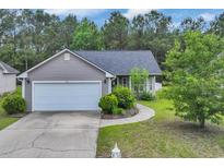 Charming single-story home with a well-manicured lawn, gray siding and attached two-car garage and driveway at 184 Retreat Pl., Little River, SC 29566