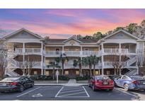 Two-story condo building with white siding, balconies, and ample parking at 5825 Catalina Dr. # 1234, North Myrtle Beach, SC 29582