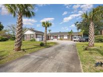 Brick ranch house with palm trees, long driveway, and attached garage at 1530 Deer Park Ln., Surfside Beach, SC 29575