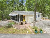 Charming home featuring a screened-in porch, yellow front door, and well-maintained landscaping at 2102 Calabash Circle, Little River, SC 29566