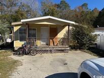 Yellow single-wide mobile home with wooden deck and small yard at 3586 Cluster Ln., Myrtle Beach, SC 29579