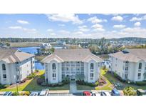 Beautiful waterfront condo complex with manicured lawn, water views, and ample parking on a sunny day at 4413 Eastport Blvd. # F-6, Little River, SC 29566