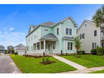 Two-story light green house with a front porch, landscaped yard, and walkway at 946 Crystal Water Way, Myrtle Beach, SC 29579