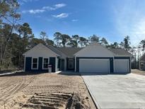 Charming new construction home featuring a three-car garage, white gables and a freshly poured concrete driveway at 25 Northbrook Dr, Murrells Inlet, SC 29576