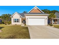 Suburban home with two-car garage, well-manicured lawn, and neutral color scheme at 409 Carrick Loop, Longs, SC 29568