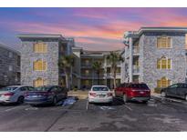 Gray brick condo building with parking and palm trees at 4705 Wild Iris Dr. # 105, Myrtle Beach, SC 29577