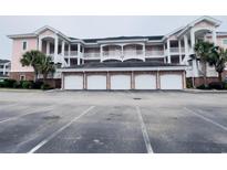 Three-story condo building featuring brick-based garages and pink siding at 4846 Carnation Circle # 203, Myrtle Beach, SC 29577