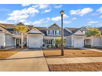 Charming townhome featuring a gray exterior, attached garage, and well-maintained landscaping under a bright blue sky at 626 Lorenzo Dr. # 626, North Myrtle Beach, SC 29582