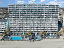 Expansive oceanfront building featuring private balconies, a pool, hot tub, and direct beach access at 1012 N Waccamaw Dr. # 1204, Garden City Beach, SC 29576