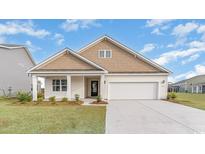 Two-story house with a light brown exterior, white garage door, and landscaping at 1118 Barrington Way, Conway, SC 29526