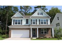 Two-story home with brick and light-green vinyl siding, a white door, and a two-car garage at 7027 Shooting Star Way, Myrtle Beach, SC 29579