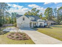 White farmhouse exterior with gray roof, two-car garage, and landscaped yard at 735 Tyson Dr., Pawleys Island, SC 29585