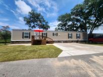Tan mobile home with deck, red umbrella, and landscaped yard at 818 Wayne St., North Myrtle Beach, SC 29582