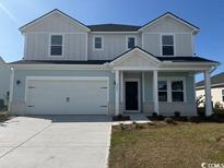 Two-story home with light blue and gray siding, a two-car garage, and a landscaped lawn at 8705 High Banks Way, Longs, SC 29568