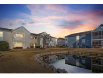 Beautiful sunset view of condos overlooking a serene pond with lush landscaping and a palm tree at 8925 Duckview Dr. # C, Surfside Beach, SC 29575