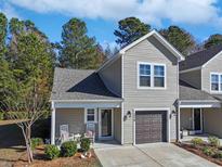 Cute two-story home with gray siding, a dark brown garage door, and rocking chairs on the front porch at 132-A Machrie Loop # A, Myrtle Beach, SC 29588