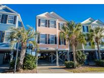 Charming raised beach home featuring a colorful exterior, black shutters, and palm trees at 2022 N Waccamaw Dr., Garden City Beach, SC 29576