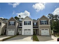 New townhomes displaying varied siding, black shutters, one-car garages, and concrete driveways at 265 Christiana Ln. # A, Myrtle Beach, SC 29579