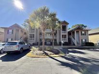 Condo building exterior featuring palm trees and well-maintained landscaping on a sunny day at 270 Pinehurst Dr. # 9-I, Pawleys Island, SC 29585