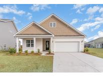 House exterior features a tan and white color scheme, a two-car garage, and a covered porch at 7085 Shooting Star Way, Myrtle Beach, SC 29579