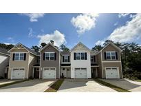 New townhomes featuring varied siding, black shutters, one-car garages, and private driveways under a partly cloudy sky at 265 Christiana Ln. # C, Myrtle Beach, SC 29579