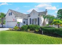 White two-story house with gray shutters, a white picket fence, and a well-manicured lawn at 5508 Whistling Duck Dr., North Myrtle Beach, SC 29582