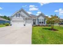 Charming gray home featuring a two-car garage, lovely landscaping, and a well-manicured lawn at 10 Grace Bay Ct., Pawleys Island, SC 29585
