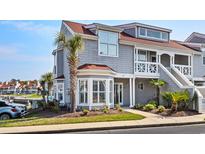 Inviting two-story condo featuring a bay window, complemented by well-maintained landscaping and a clear blue sky at 4396 Baldwin Ave. # 34, Little River, SC 29566