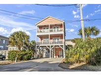 Charming, raised beach house featuring double balconies and lush, tropical landscaping at 124 Rainbow Dr., Murrells Inlet, SC 29576