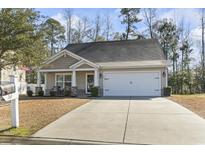 Charming single-story home featuring a two-car garage, landscaped front yard, and inviting covered porch at 261 Sea Turtle Dr., Myrtle Beach, SC 29579
